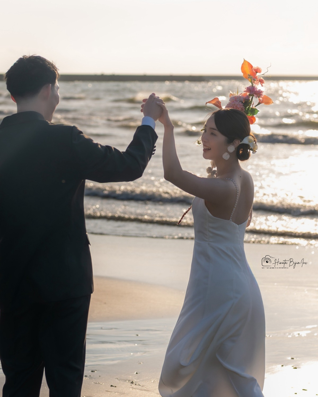 海辺で手を取り合うドレス姿の花嫁と新郎