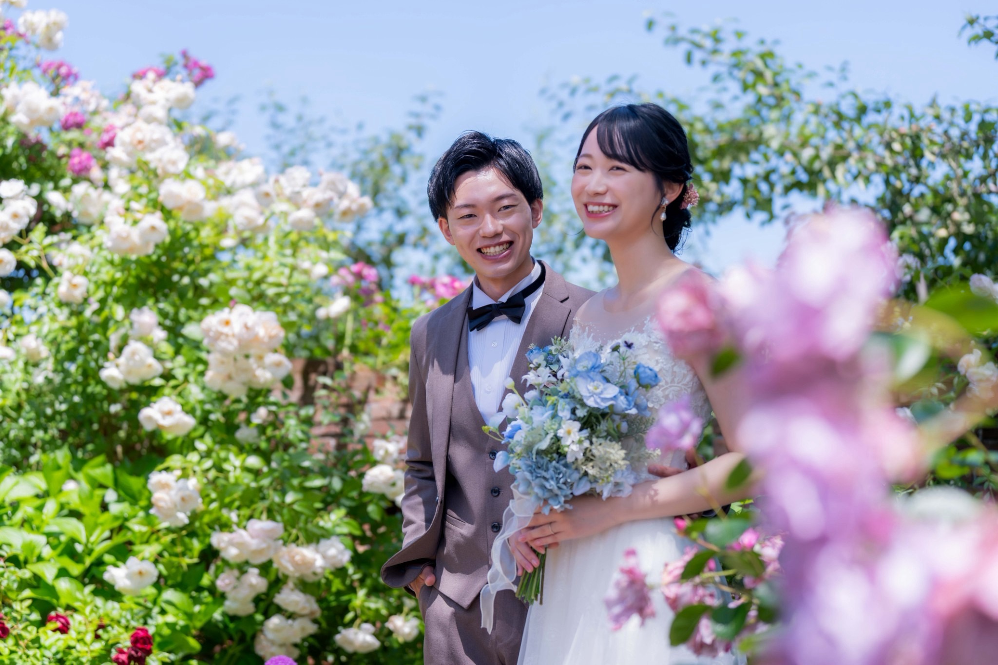 花に囲まれて笑顔を見せる新郎新婦