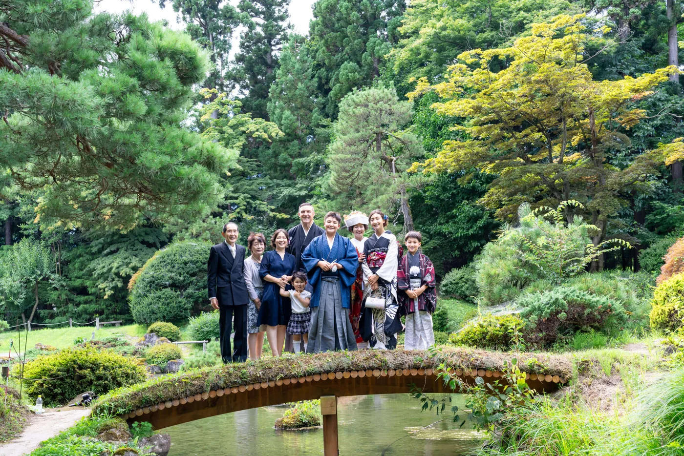 和装の新郎新婦を囲み、庭園で一緒に記念撮影をするご家族